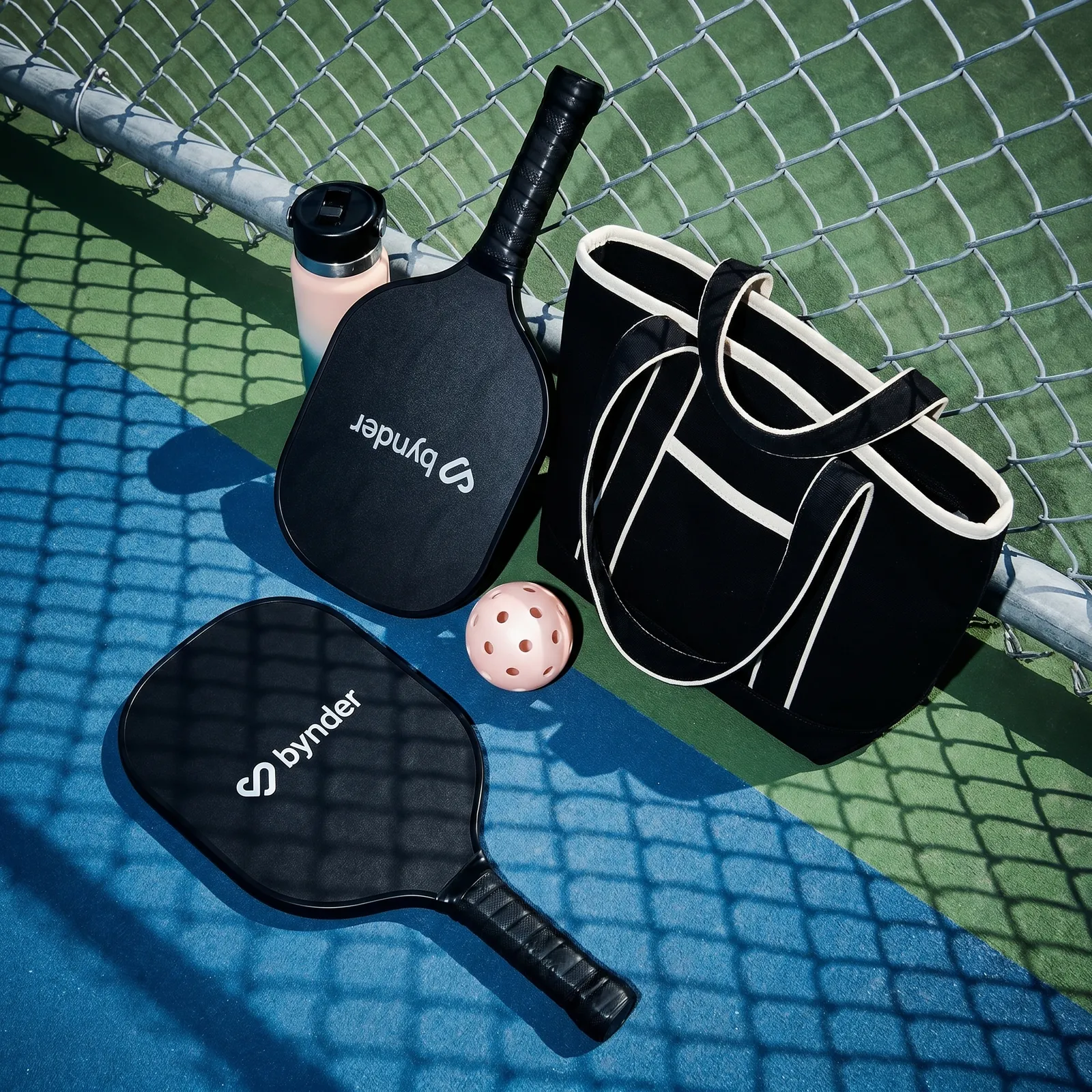 Branded pickleball paddles, ball and tote bag on a court