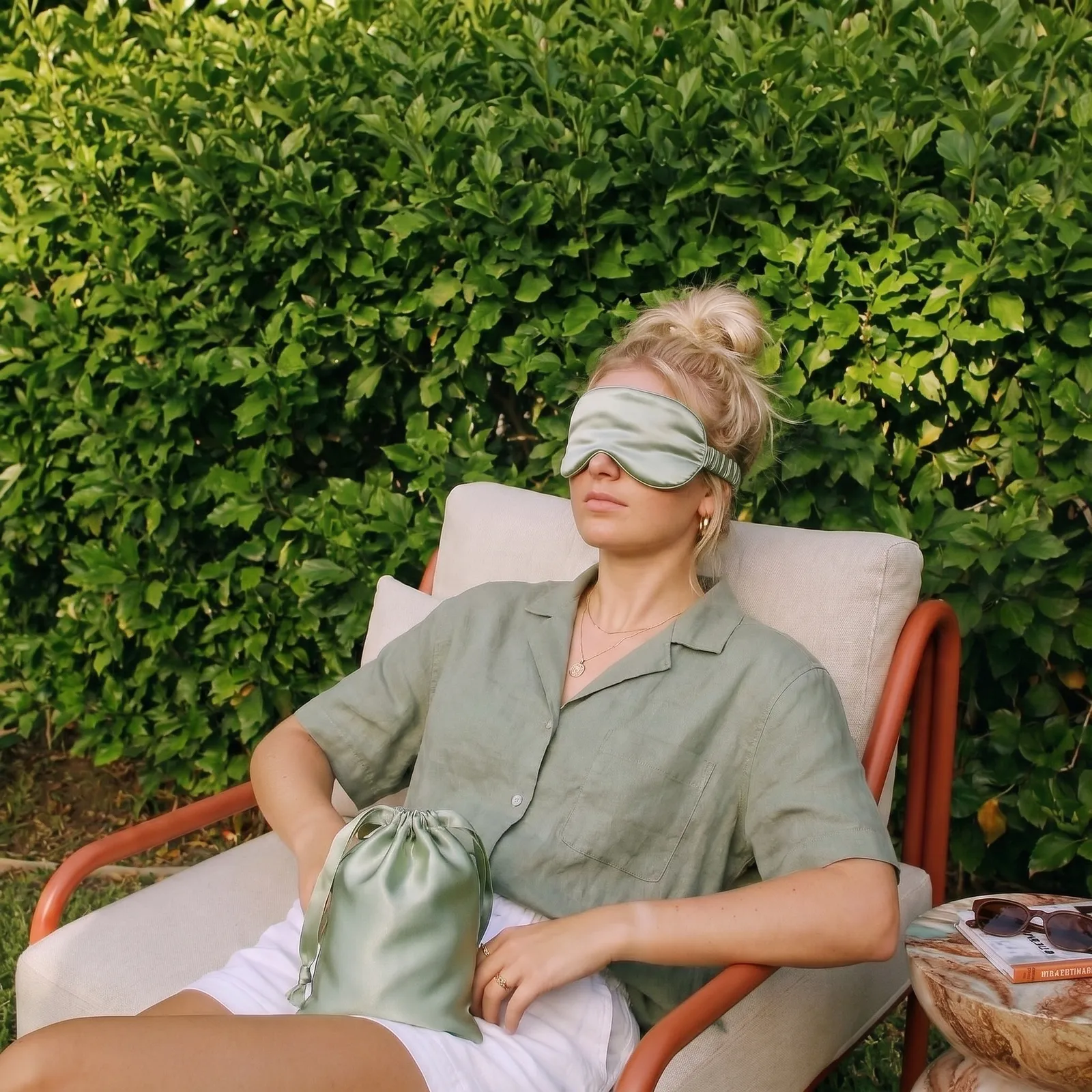 Person relaxing outdoors wearing a branded silk eye mask