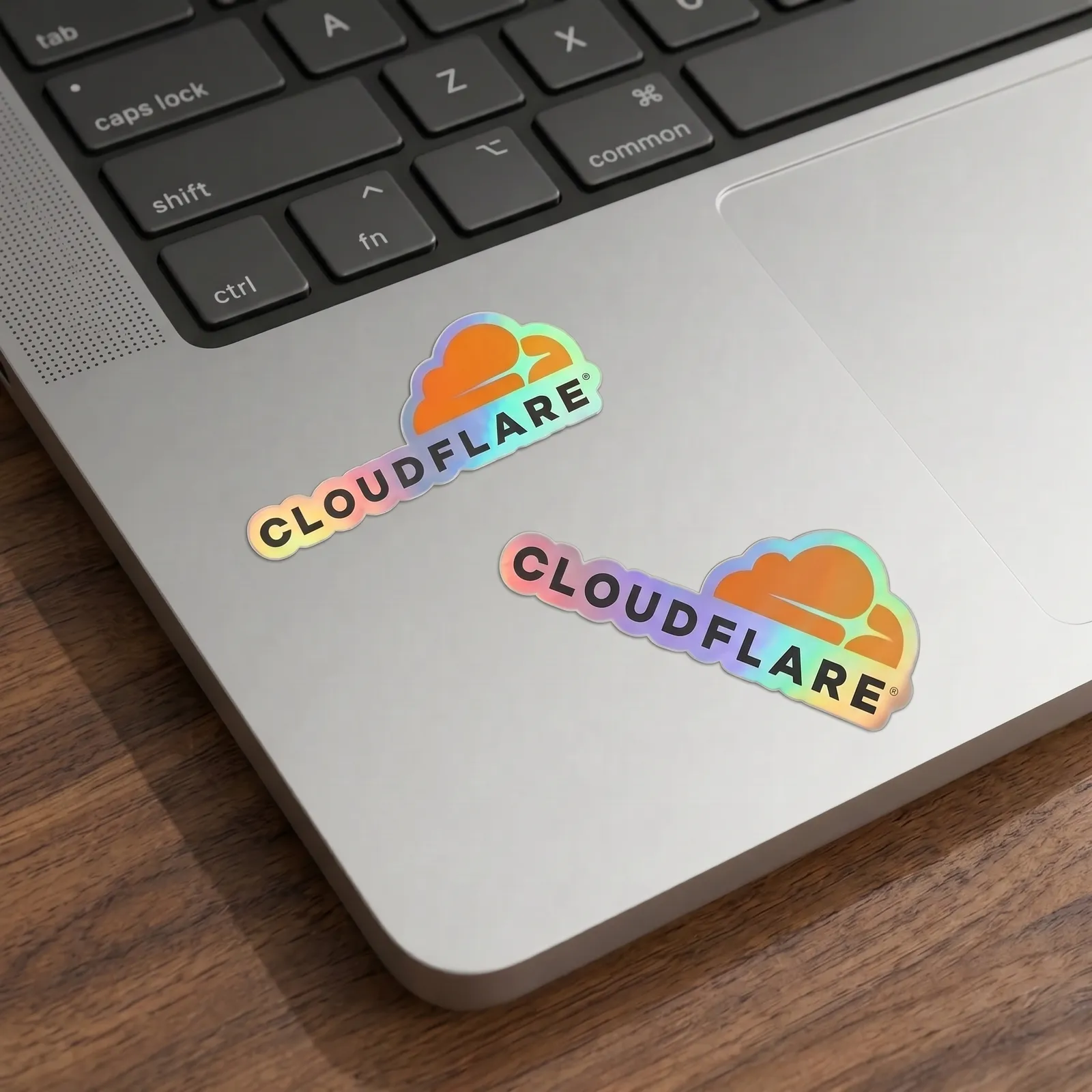 Two holographic Cloudflare stickers on a laptop